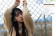 A woman standing in front of a chain link fence.