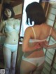 A woman in a white bra and panties looking at herself in the mirror.