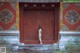 A naked woman standing in front of a wooden door.