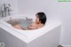 A woman sitting in a bathtub with water in it.