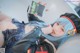 A woman with blue hair and a black jacket holding a book.