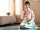 A woman in a kimono sitting on the floor in a room.