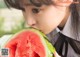 A young woman is eating a slice of watermelon.