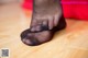 A close up of a person's feet in black stockings on a wooden floor.