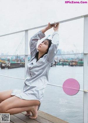 A woman in a white shirt is sitting on a dock.