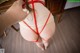 A woman is tied up with a red rope.