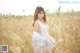 A woman in a white dress sitting in a field.