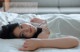 A woman laying on a bed in a white dress.