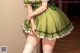 A woman in a green dress and white stockings posing for a picture.