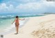 A woman in a bikini running on the beach.