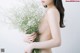 A naked woman holding a bunch of baby's breath.