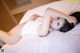 A woman laying on top of a white bed.